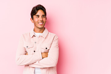 Young caucasian man posing in a pink background isolated smiling confident with crossed arms.