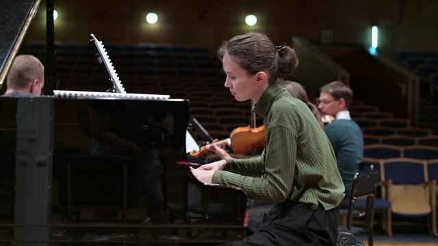 The pianist accompanies the string orchestra. Musicians rehearsing performance at the Conservatory