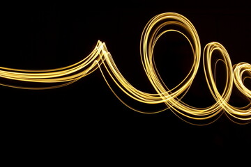 Long exposure photograph of neon gold colour in an abstract swirl, parallel lines pattern against a...