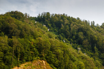 Misty mountain landscape with fir forest. Beautiful landscape with mountain view, cable car. Postcard view. Travel concept. Sunset, Golden hour