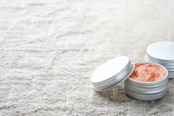 Two jars of natural cosmetic product on a linen napkin