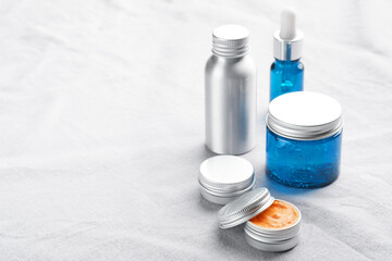 Set of metal and glass containers of natural cosmetic products on linen fabric