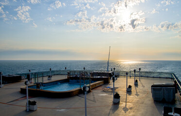 View over after deck with swimming pool on luxury cruiseship or cruise ship liner onto horizon with...