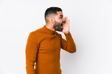 Young latin man against a white background isolated shouting and holding palm near opened mouth.