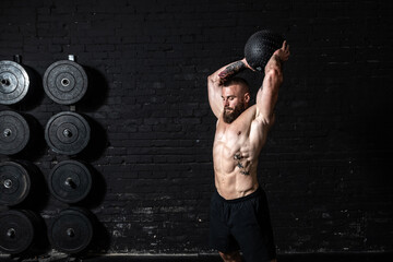 Young sweaty strong muscular fit man with big muscles doing ball throwing on the floor as hardcore...