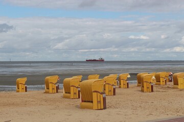 Beach chairs on a sandy beach by the North Sea. View of the wadden sea. Cuxhaven, North Germany,...