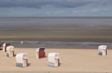 Beach chairs on a sandy beach by the North Sea. View of the wadden sea. Cuxhaven, North Germany,...