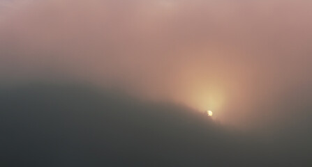 Detail of sun going up at sunrise through trees and misty fog. Toned photo, Czech landscape