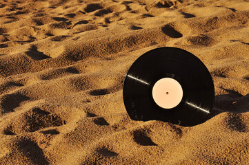 Vinyl record disk on a sandy beach.