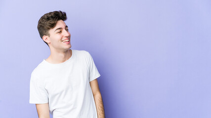Young caucasian man isolated on purple background relaxed and happy laughing, neck stretched showing teeth.