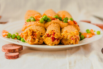 Gluten-free keto Crepes filled with paprika hummus in the oven with curry sauce and sweet corn and green peas on top
