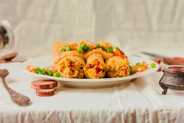 Gluten-free keto Crepes filled with paprika hummus in the oven with curry sauce and sweet corn and green peas on top