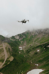 Fototapeta na wymiar Flying photography drone in the cloudy sky in the mountains, moody weather, natural colors