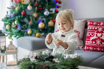 Little cute blonde toddler boy, making advent wreath at home