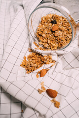 Healthy homemade granola muesli porridge with oats, nuts, dried berries on a white checkered towel