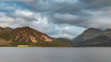 Stunning landscape image looking across Ennerdale Water in the English Lake District towards the peaks of Scoat Fell and Pillar during a glorious Summer sunset
