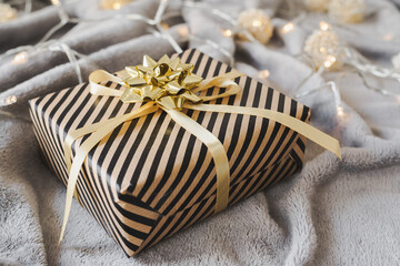 Gift box wrapped in craft paper with golden ribbon and bow. Christmas present wrapping idea. Eco friendly gift wrap