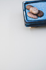Vertical shot of pebbles on a rectangular box filled with small blue rocks on white background