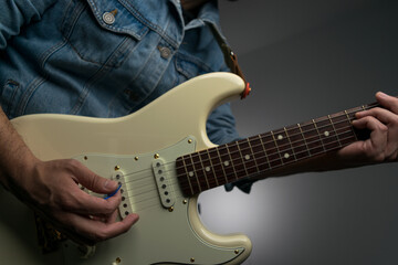 Obraz premium Man playing white electric guitar on a jean jacket
