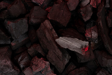 Smoldering charcoal with ash background. Incandescent red embers texture. Dark background.
