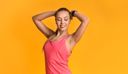 Beautiful fitness model with perfect sporty body posing on yellow background