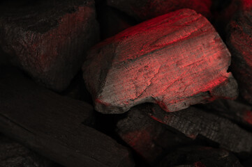 Smoldering red coal with ash background. Big cracked piece of smoldering charcoal close up....