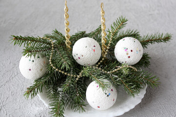 White Christmas balls and fir twigs in the snow. Christmas composition. Blurred background.