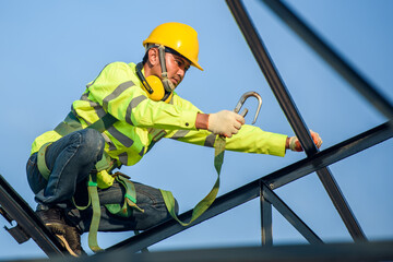 Asian construction worker Wear safety clothing and harnesses to do construction work on steel roof...