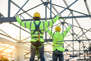 Asian construction worker Wear safety clothing and harnesses to do construction work on steel roof structures.