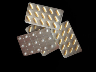 Medicamentos en paquetes con diferentes tipos de pastillas dentro, sobre fondo negro.