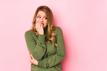 Young caucasian woman isolated on pink background biting fingernails, nervous and very anxious.