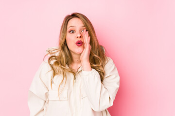 Young caucasian woman isolated on pink background is saying a secret hot braking news and looking aside