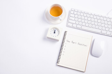 Conceptual,mouse and keyboard with clock and tea on white blackground work space.open diary with new year's resolutions 2017.