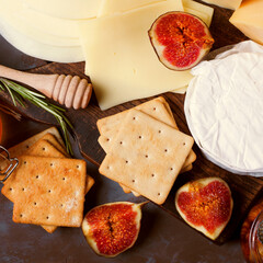 Cheese board with brie, maasdam, gouda and goat cheese, figs, honey and jam. Appetizer assortment on the grey table