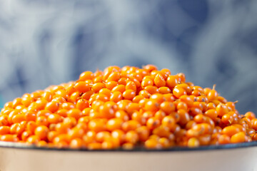 Heap of ripe orange sea buckthorn in enamelware