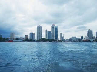 Bangkok city in rainy weather, view from the water. Thailand’s capital, Chao Phraya River. Skyscrapers, boats, urban modern architecture. Thailand, monsoon season, storm, sky, storm clouds, cityscape