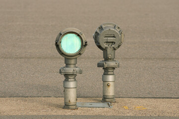 Two green lanterns on the asphalt background. Airport navigation lights, horizontal photography.