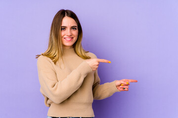 Young caucasian woman isolated on purple background shocked pointing with index fingers to a copy space.