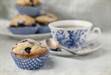 Original food still life photograph of homemade blueberry muffins with a blue teacup on gray