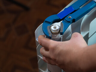 twist the nuts with an adjustable wrench in the radiators. installing radiators in the house. men's hand.