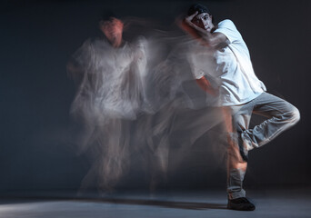 Stylish young guy rapper stands in neon light. Long exposure shot. Battle competition announcement