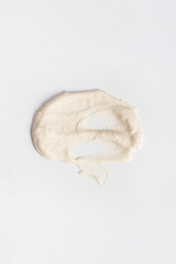 White cosmetic cream smears on a white background. Skin care lotion serum texture sample. Closeup of a beauty product sample.