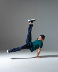 Cool b-boy dancing in studio isolated on gray background with copy space. Dancing school poster