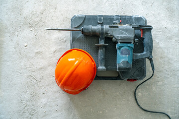 Dismantling works background. Rotary hammer for construction destroying and hardhat on the...