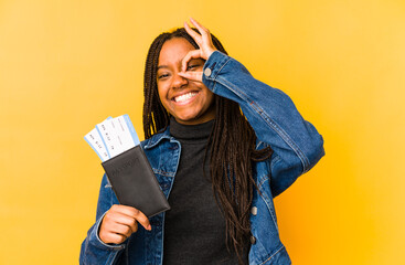 Young african american woman holding a passport isolated excited keeping ok gesture on eye.