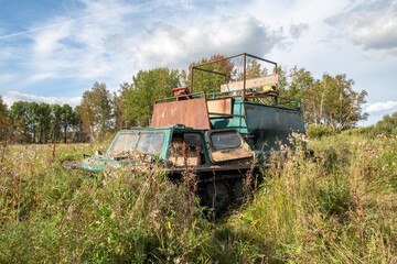 Fototapeta premium An old military tracked tractor built in the 70s of the last century in the Soviet Union on a hunting trip in the autumn forest