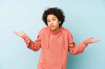 African american little boy isolated doubting and shrugging shoulders in questioning gesture.