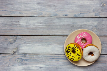 Colored donuts on wooden background top view