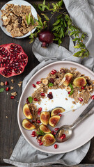 Bowl of greek yogurt with granola , fresh fig and pomegranate seeds