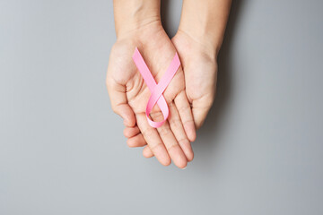 Obraz premium October Breast Cancer Awareness month, adult Woman hand holding Pink Ribbon on grey background for supporting people living and illness. International Women, Mother and World cancer day concept